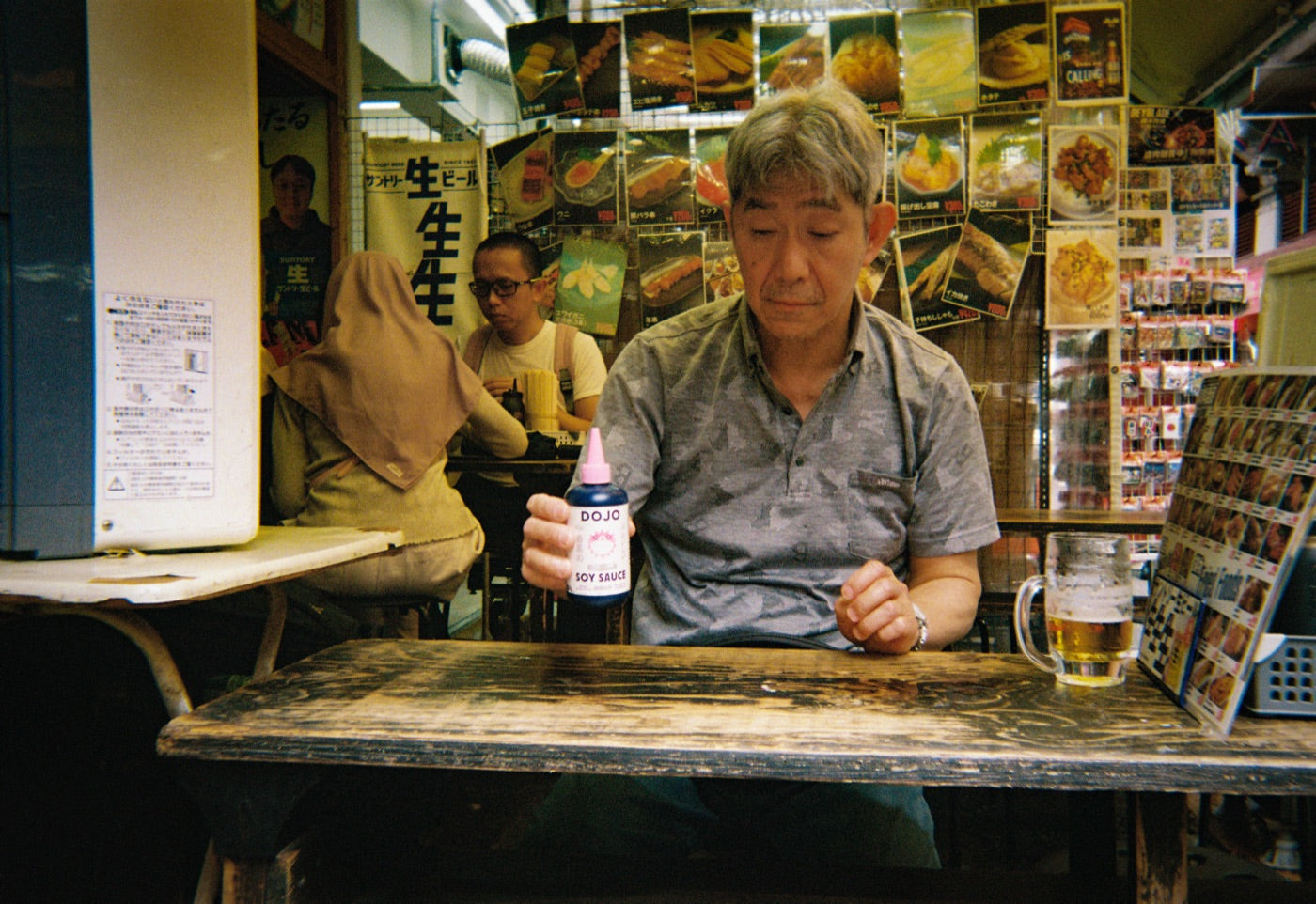An izakaya regular at his table holding the Dojo bottle