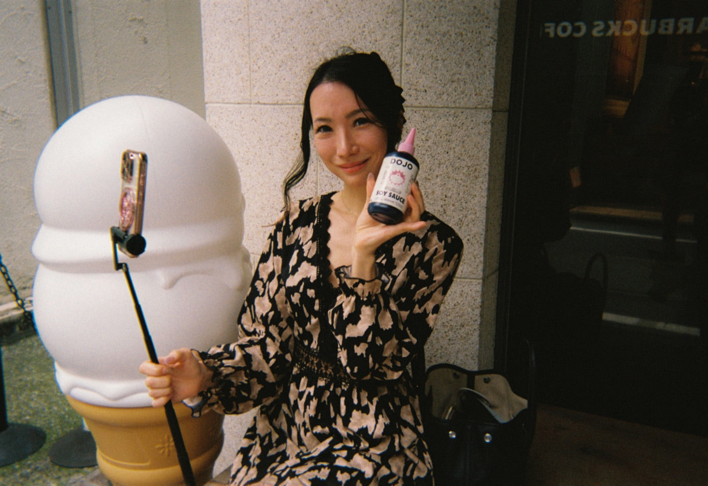 A fan posing with the bottle next to a giant soft-serve cone statue