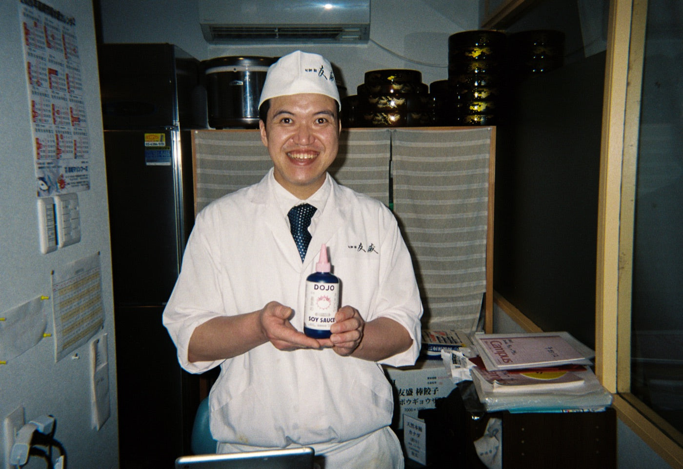 A brewer in whites holding the Dojo bottle inside the brewery office