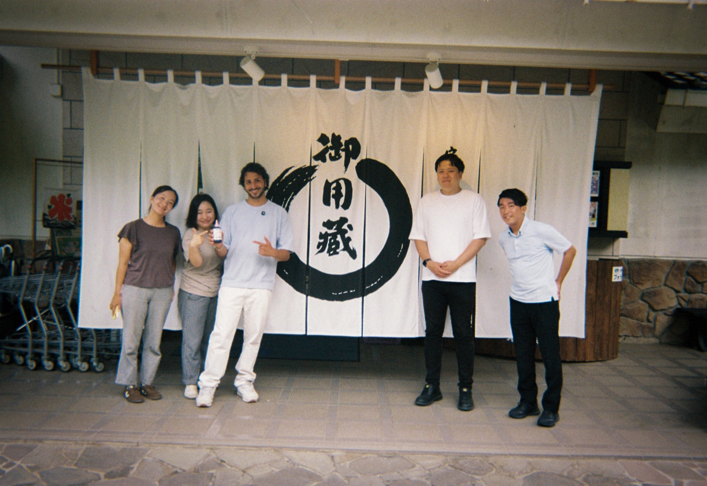 The Dojo crew and the brewers in front of the brewery's calligraphy noren