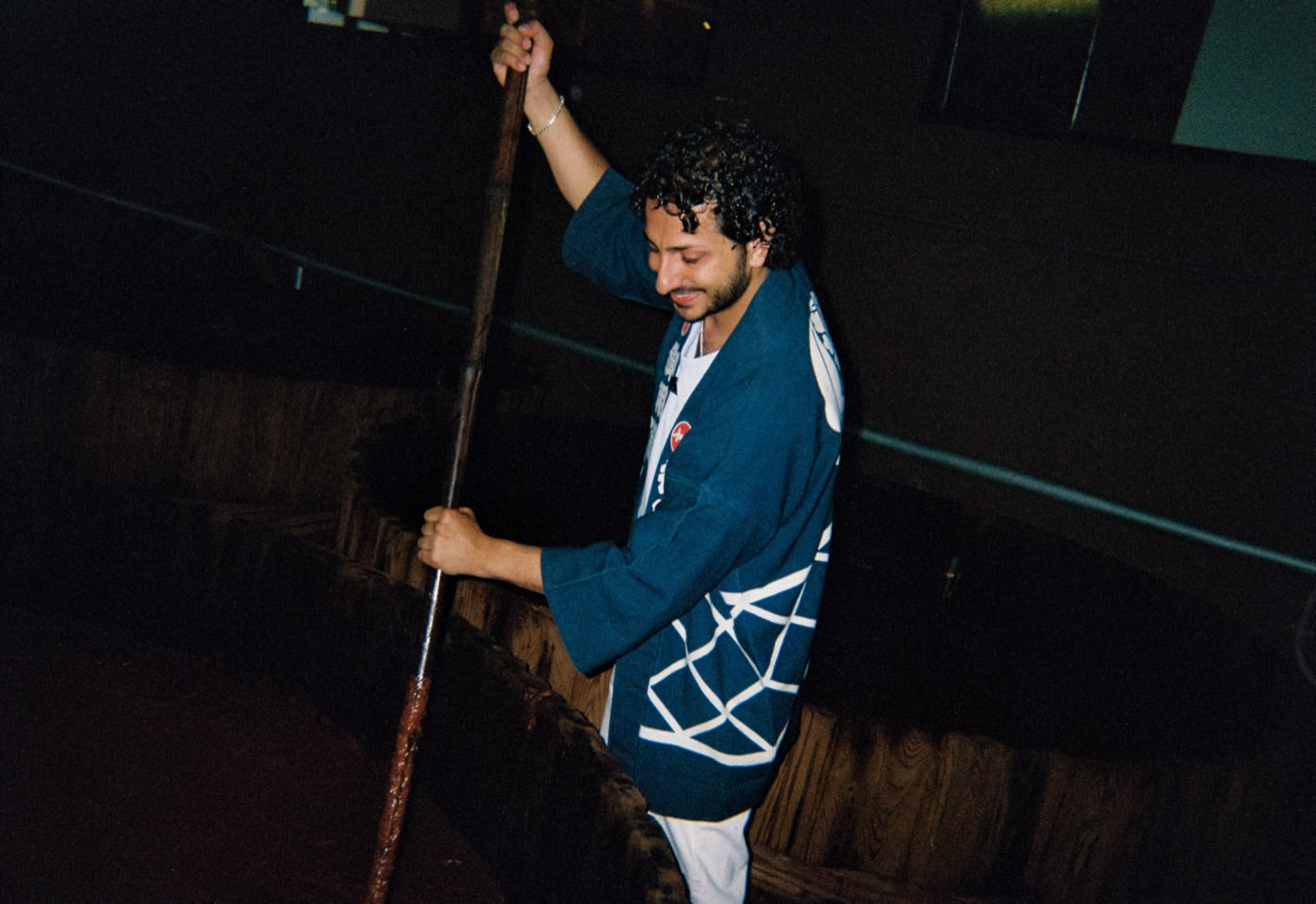 Stirring a cedar vat of moromi with a long wooden pole, in a brewer's happi coat