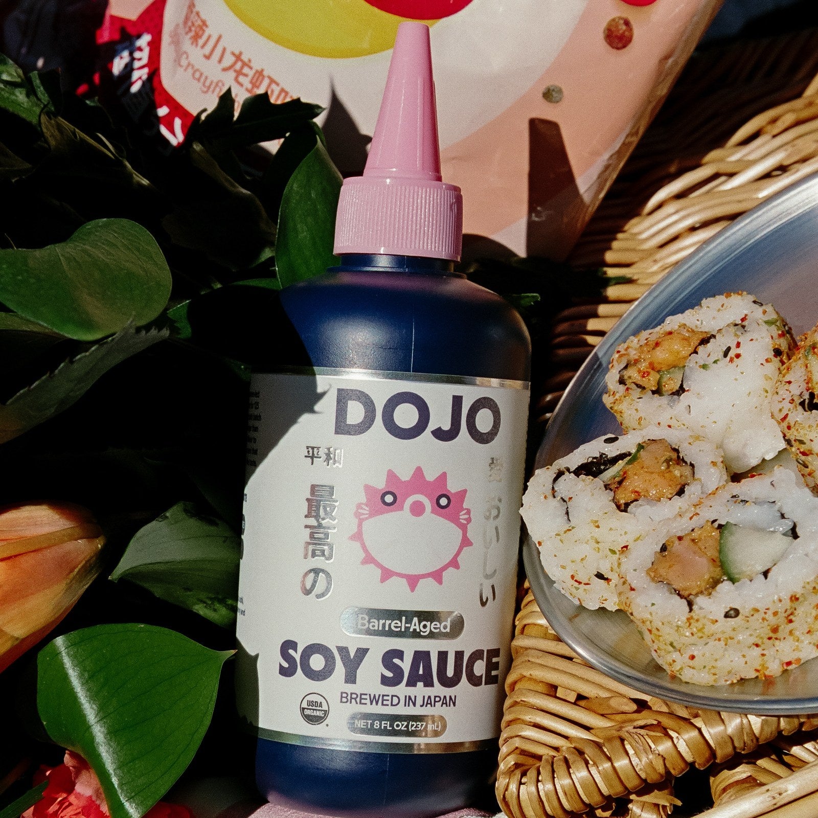 The DOJO bottle beside a picnic basket and a plate of sushi rolls