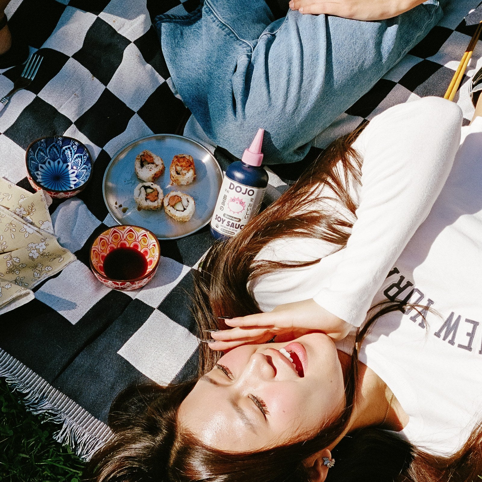 A picnic on a checkered blanket with sushi and the DOJO bottle