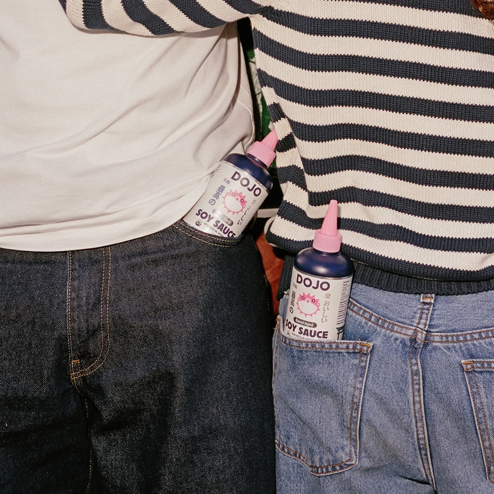 Two DOJO bottles tucked into the back pockets of two pairs of jeans